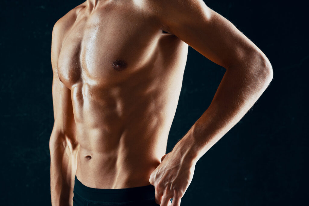 sporty man with a pumped-up muscular body in a towel dark background